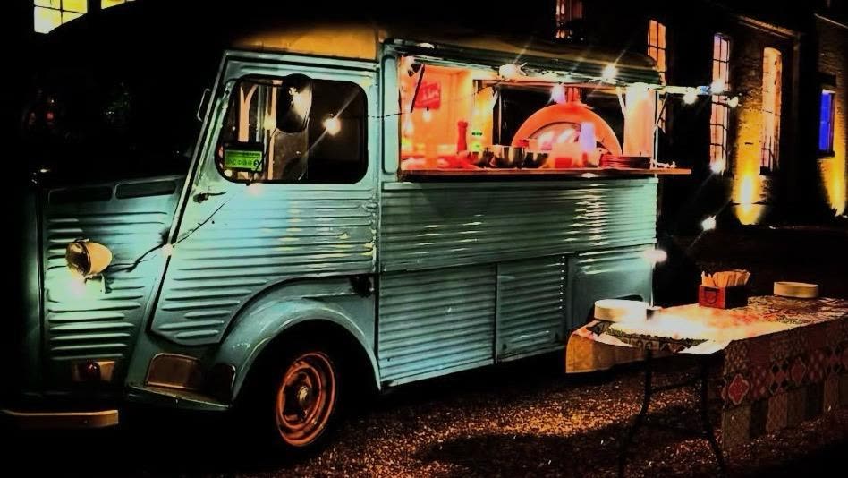 Real fire oven glowing inside the van at a festival at night
